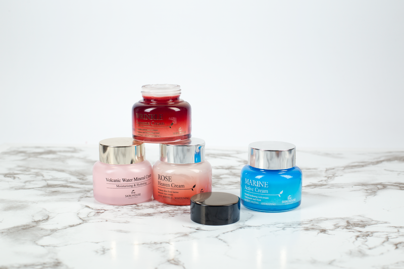 Assorted skincare cream jars arranged on a marble surface, showcasing beauty and elegance.