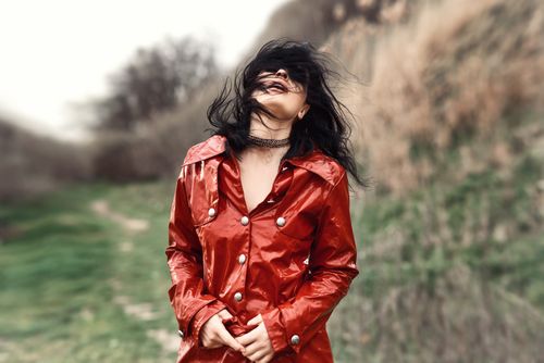 Free Fashionable woman in a red coat enjoying a windy day outdoors. Stock Photo