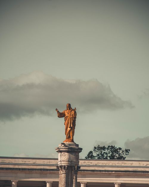 Free Majestic golden statue atop a column, set against a dramatic cloudy sky. Stock Photo