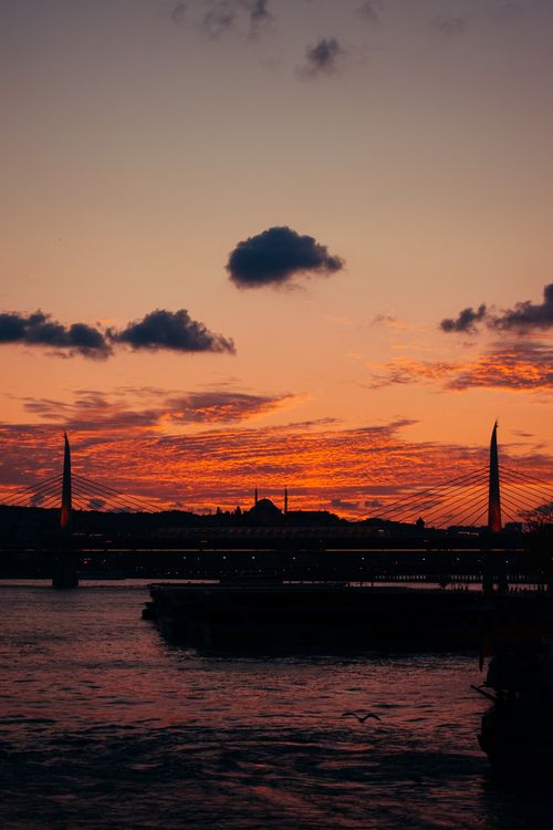 Free A stunning sunset casts vibrant hues over a city skyline with a bridge silhouette. Stock Photo