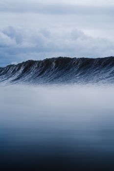 Picturesque view of dark blue seawater with large foamy wave under cloudy sky