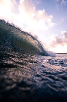 A stunning vertical shot capturing a powerful ocean wave at sunrise, highlighting the beauty of nature.