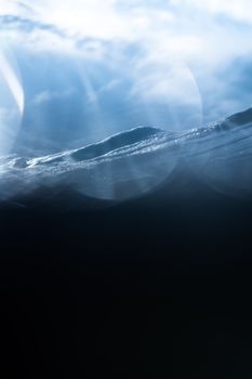 Surface of blue ocean water with waves under cloudy azure sky in sunlight