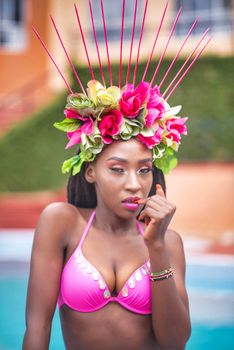 Stunning portrait of a woman in a colorful floral headdress by a pool.
