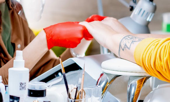 Crop anonymous master of nail salon in red gloves holding hands of unrecognizable client