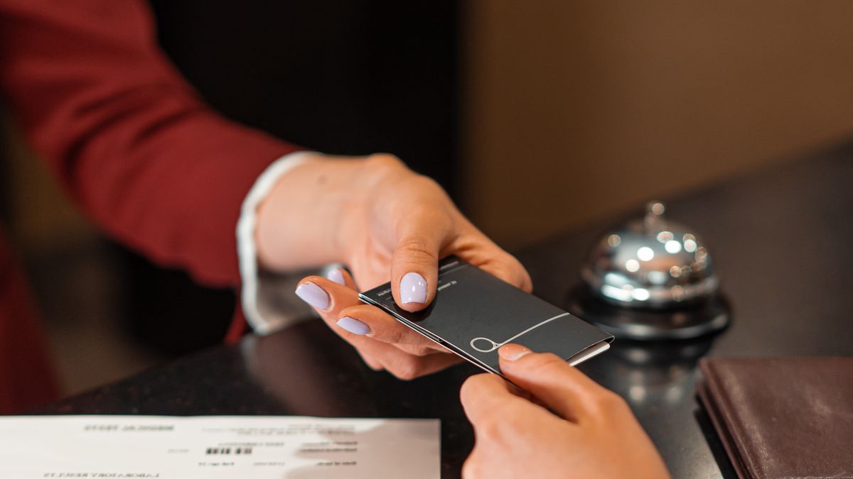 A hotel receptionist handing a key card to a guest at check-in