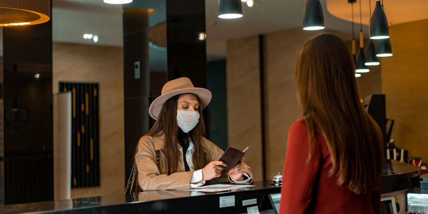 Hotel front desk with a guest being checked in by a clerk in a sleek modern lobby
