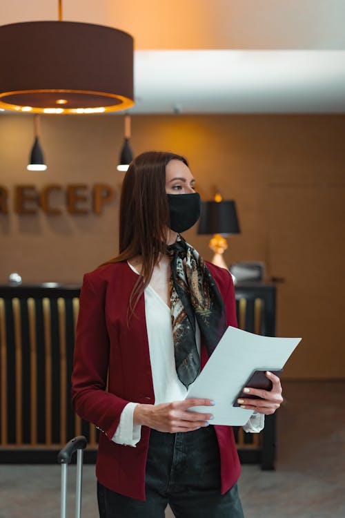 Free Female Receptionist Holding Papers and Passport Stock Photo