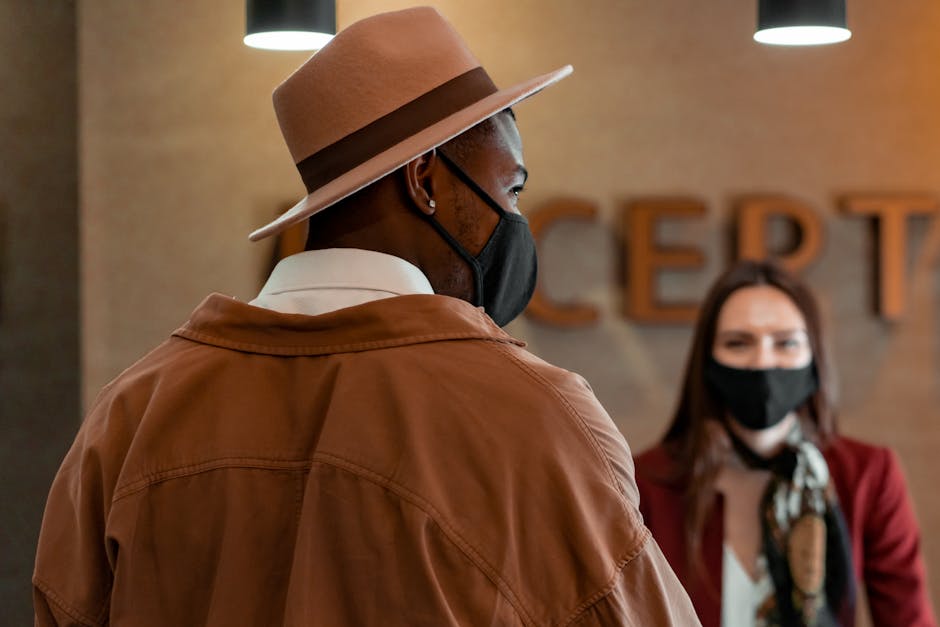 A masked tourist with a hat checks in at a hotel reception, practicing new normal protocols.