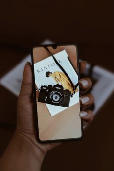 Hand displaying a smartphone showing a vintage camera, artistic and conceptual image.