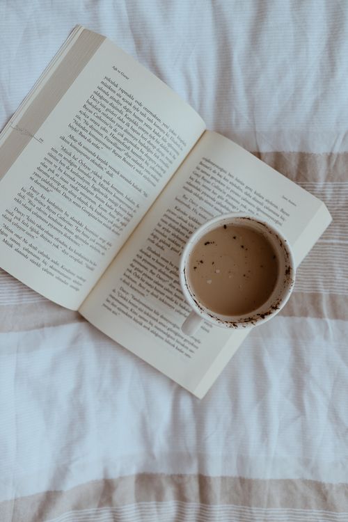 Free Relaxing scene with an open book and coffee cup on a striped blanket. Stock Photo