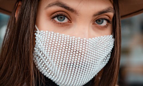 Close-Up Photo of a Woman with Blue Eyes Wearing a White Face Mask