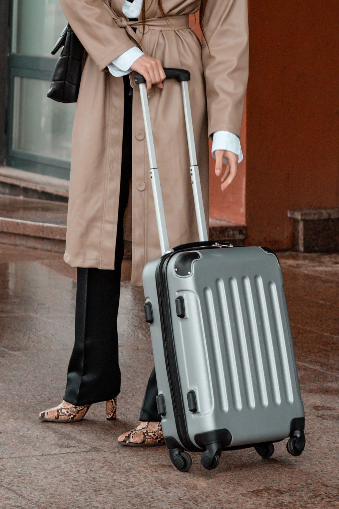 Stylish traveler in a brown coat with luggage at the airport