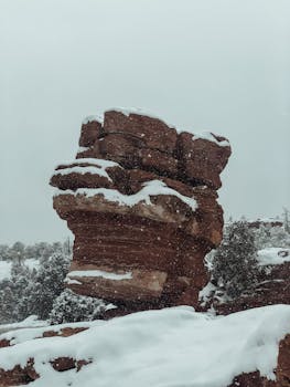 Red rock formation dusted with snow in Colorado Springs' winter landscape.