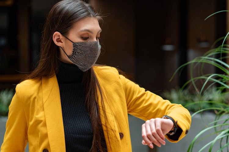 Photo Of A Woman In A Yellow Coat Looking At The Time