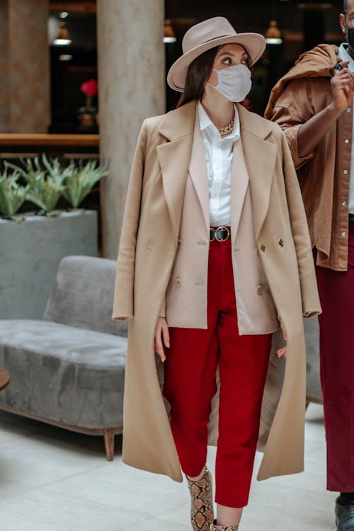 Photo of a Woman Wearing a Beige Coat and Red Pants