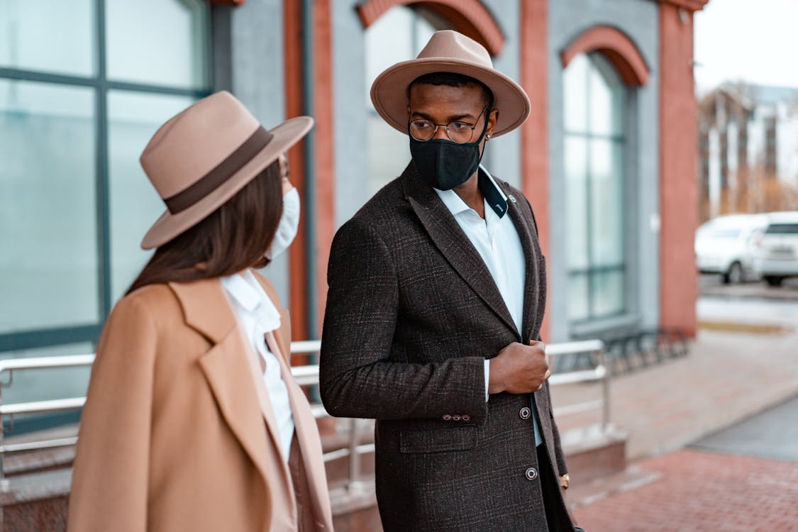 Photo of a Man in a Black Blazer Talking to a Woman with a Beige Hat