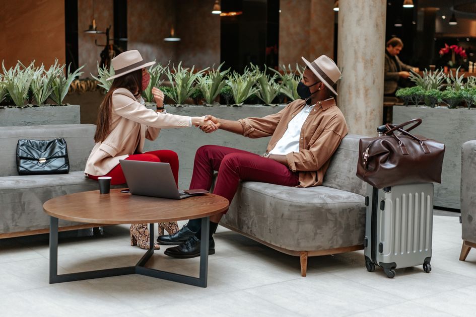 Two fashionable individuals shaking hands in a hotel lobby, showcasing travel and safety. Related image for hotel revenue strategy in Europe hotels.