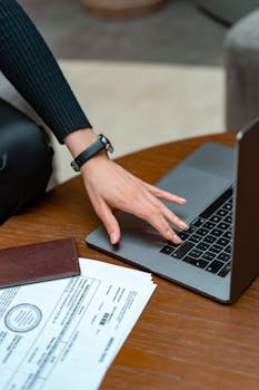 Close-up of a person typing on a laptop with legal documents on a table, showcasing work and technology integration.