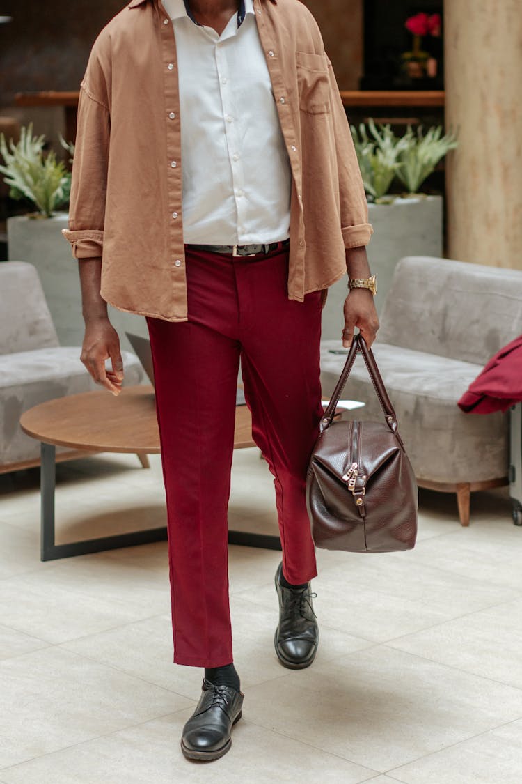 Photo Of A Man In Red Pants Carrying A Brown Leather Bag