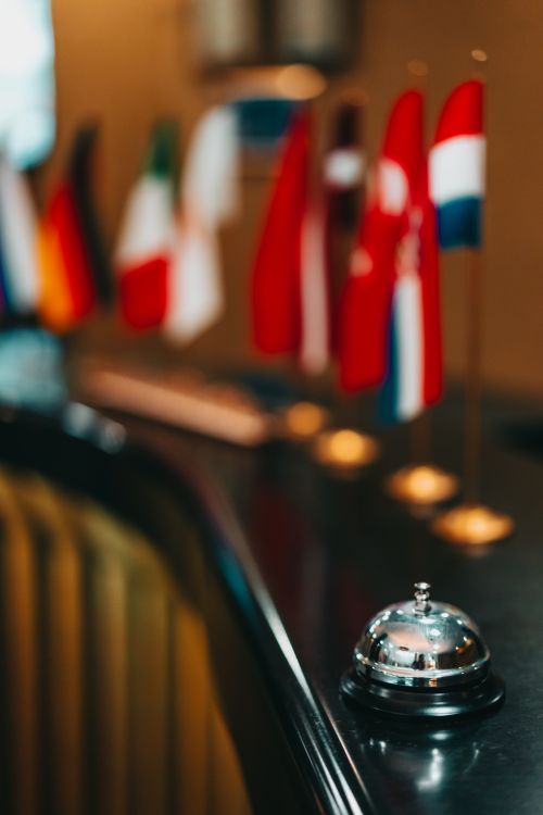 Free Elegant hotel reception desk with a focus on a service bell and international flags in soft focus. Stock Photo