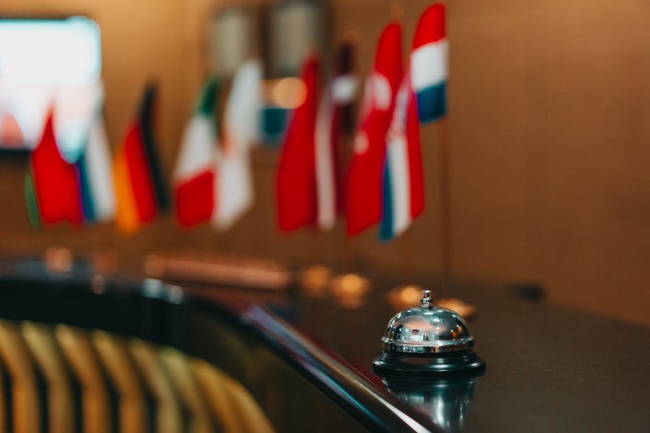 Sophisticated hotel lobby with a reception bell and array of international flags in focus. Related image for AI in hospitality in Global hotels.