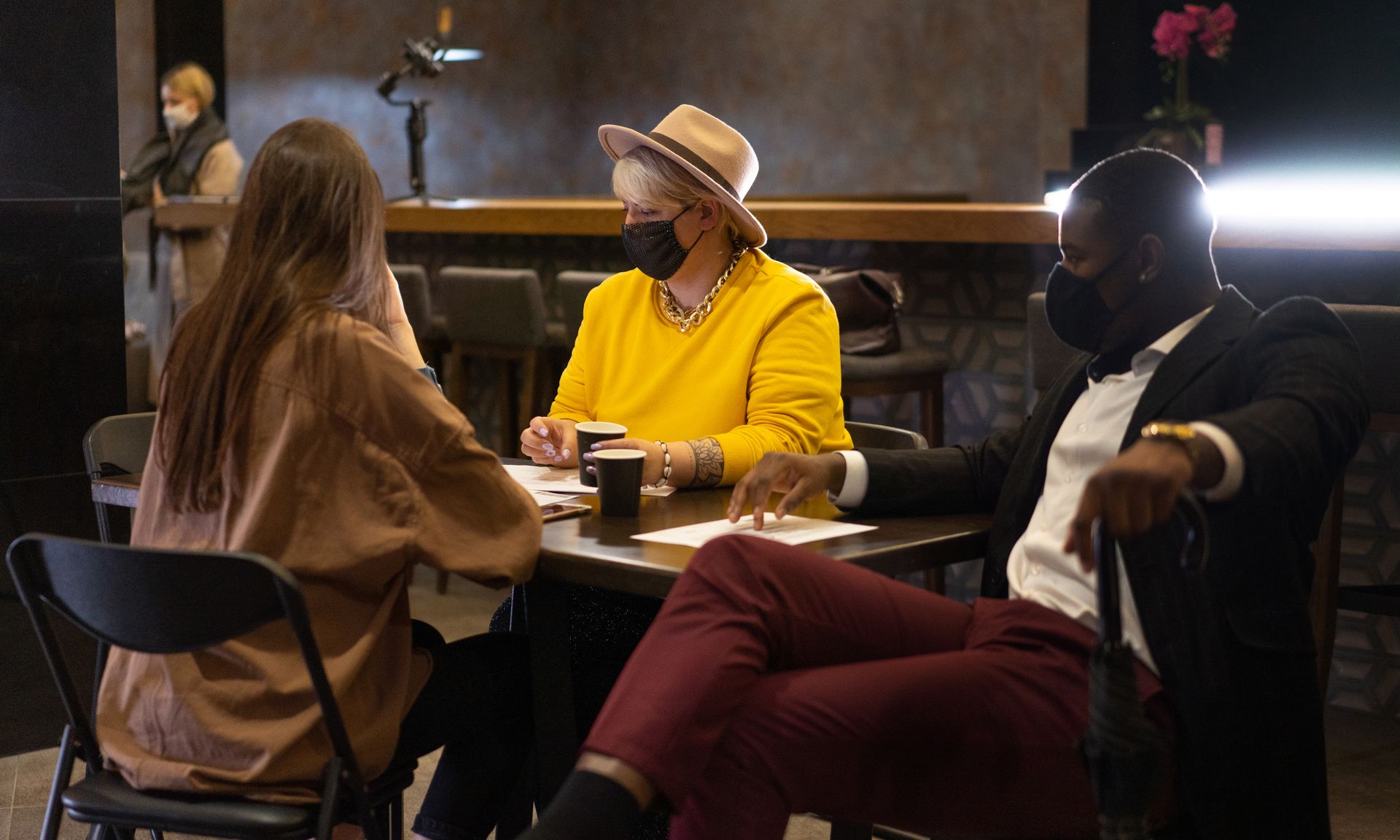 People having a discussion while wearing masks in a restaurant.