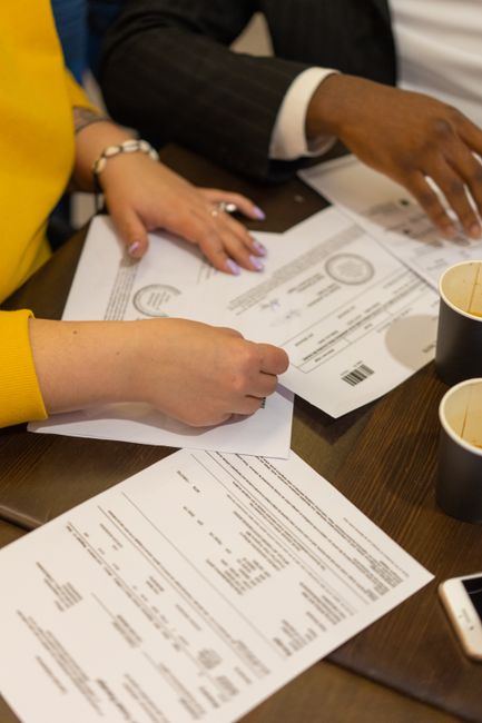 Fotomural Colegas multirraciales colaborando en una reunión de negocios, revisando documentos en una mesa de madera.