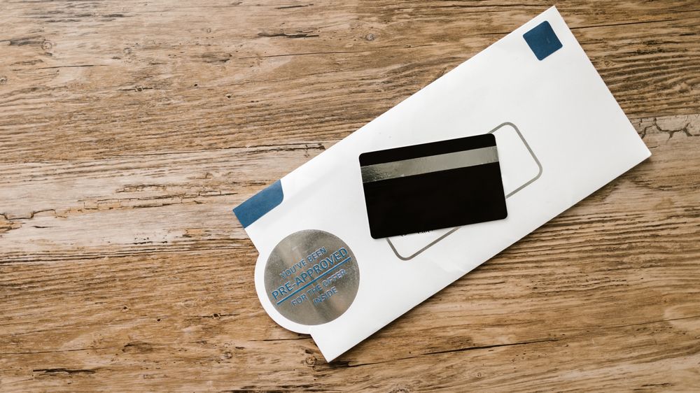 A blank credit card with a pre-approved envelope on a wooden table, showcasing financial opportunities.