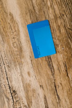 Top view of a blue card placed on a rustic wooden surface, ideal for business or technology themes.