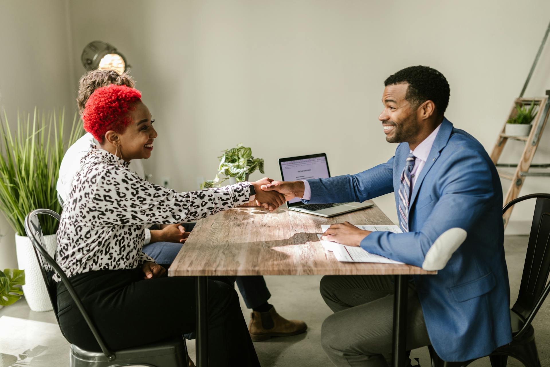 Business professionals shaking hands indoors with smiles, capturing a successful deal or agreement.