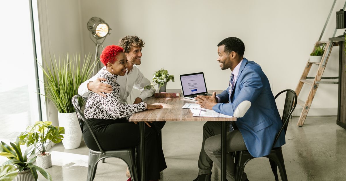 Un courtier remercie un couple de clients heureux autour d’une table
