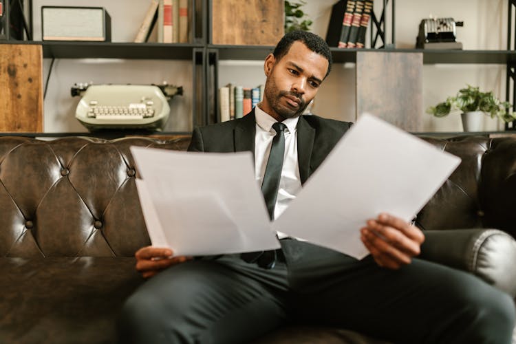 A Man In A Suit Looking At Documents