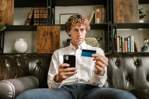 Man Holding a Card and a Cellphone