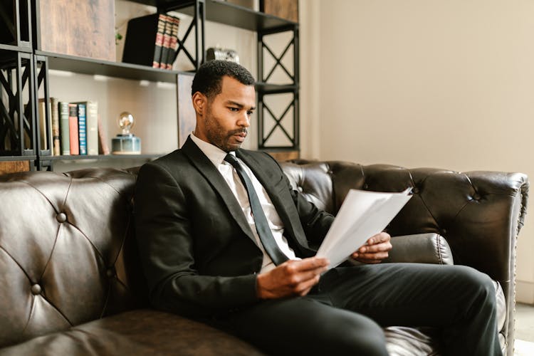 A Man In A Suit Looking At Documents