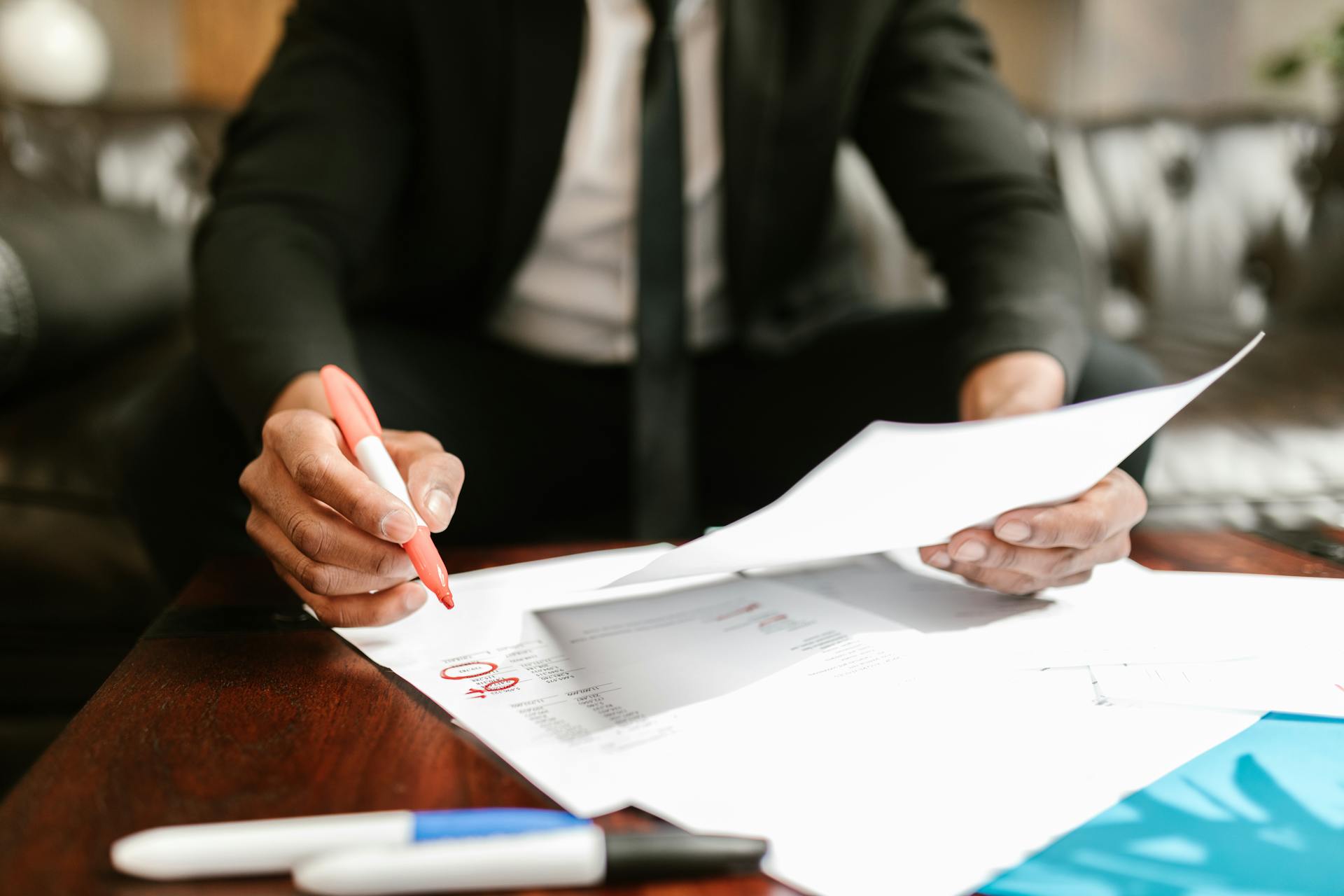 Businessman working with financial documents at office desk, highlighting details.