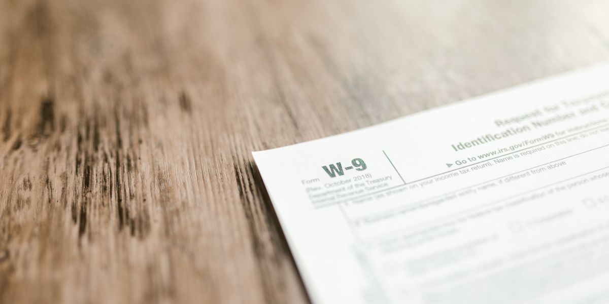 A close-up of a W-9 tax form placed on a wooden desk, emphasizing paperwork and finance.