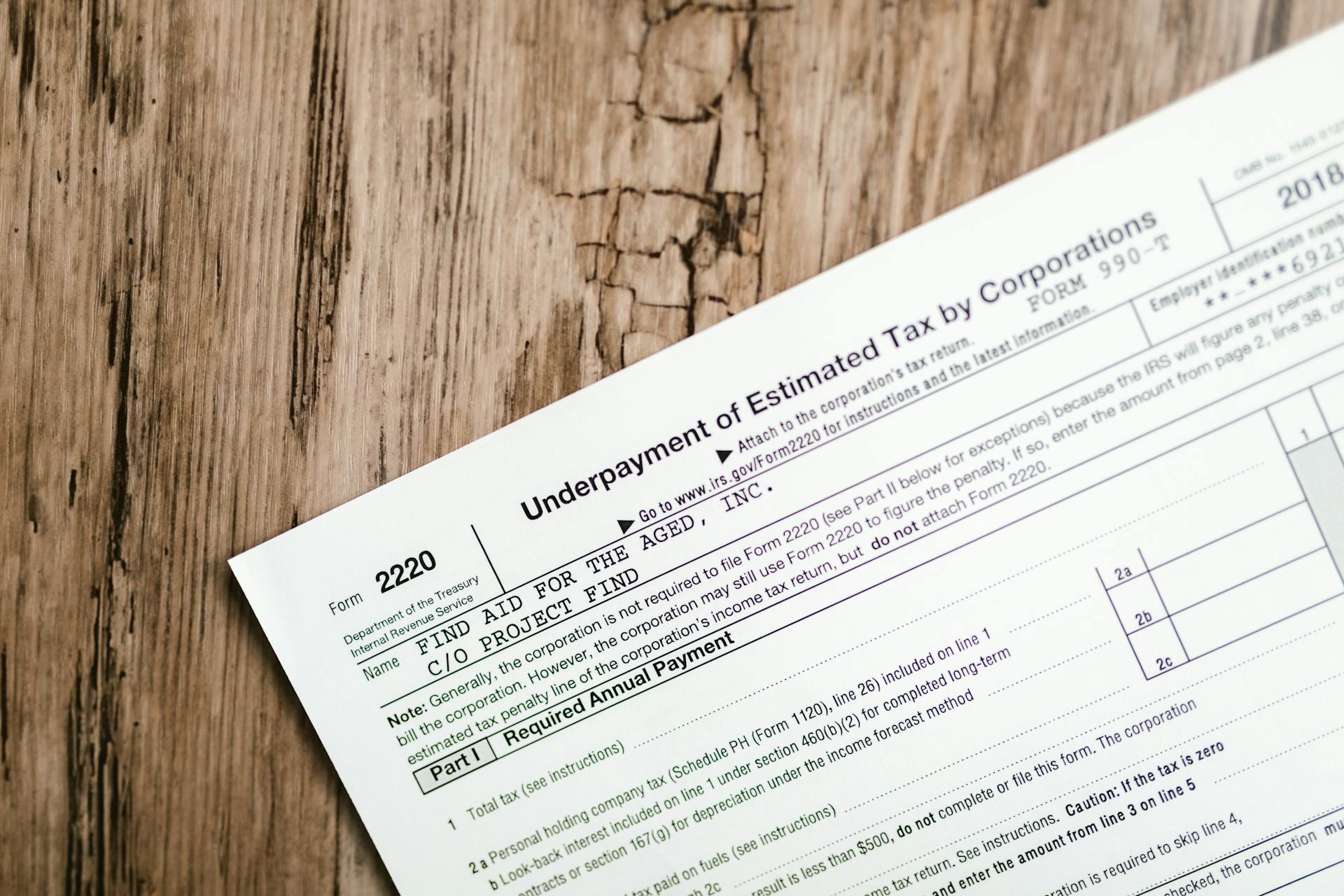 Close-up of a corporate tax form on a textured wooden surface, highlighting document details.