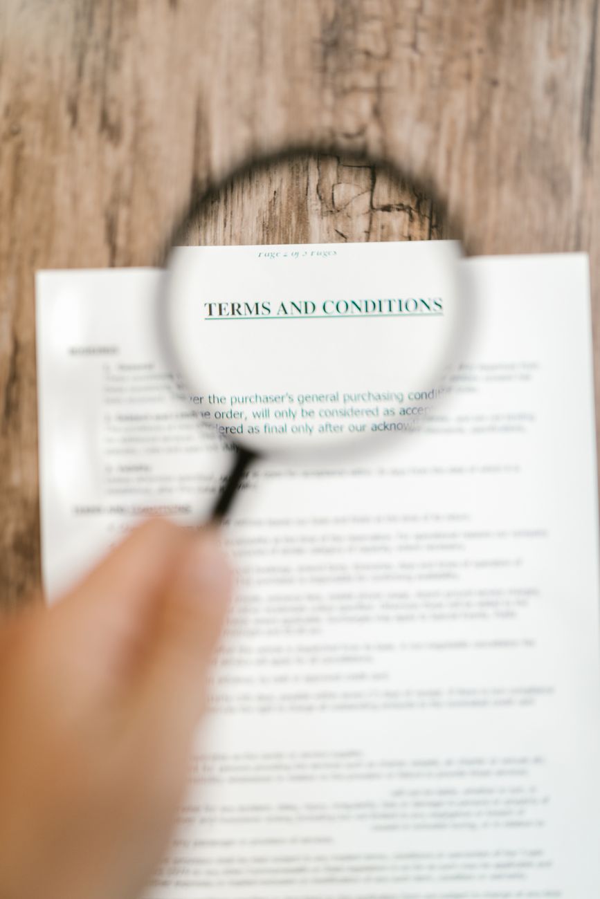 A magnifying glass over a Terms & Conditions document — reading the fine print behind 'scam' claims