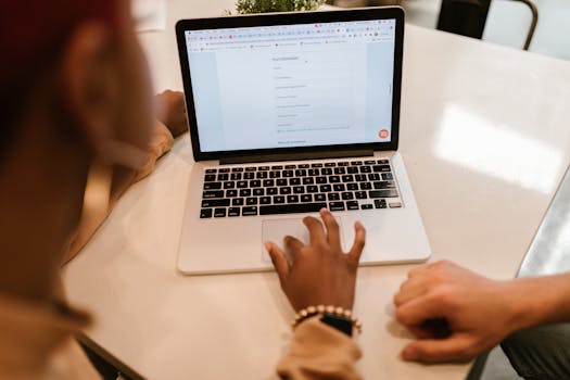 Two adults working together on a laptop displaying an online form, indoors.