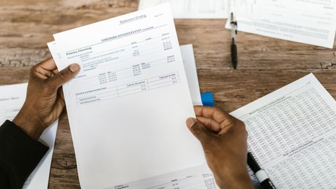 Hands holding financial papers for tax preparation and analysis.