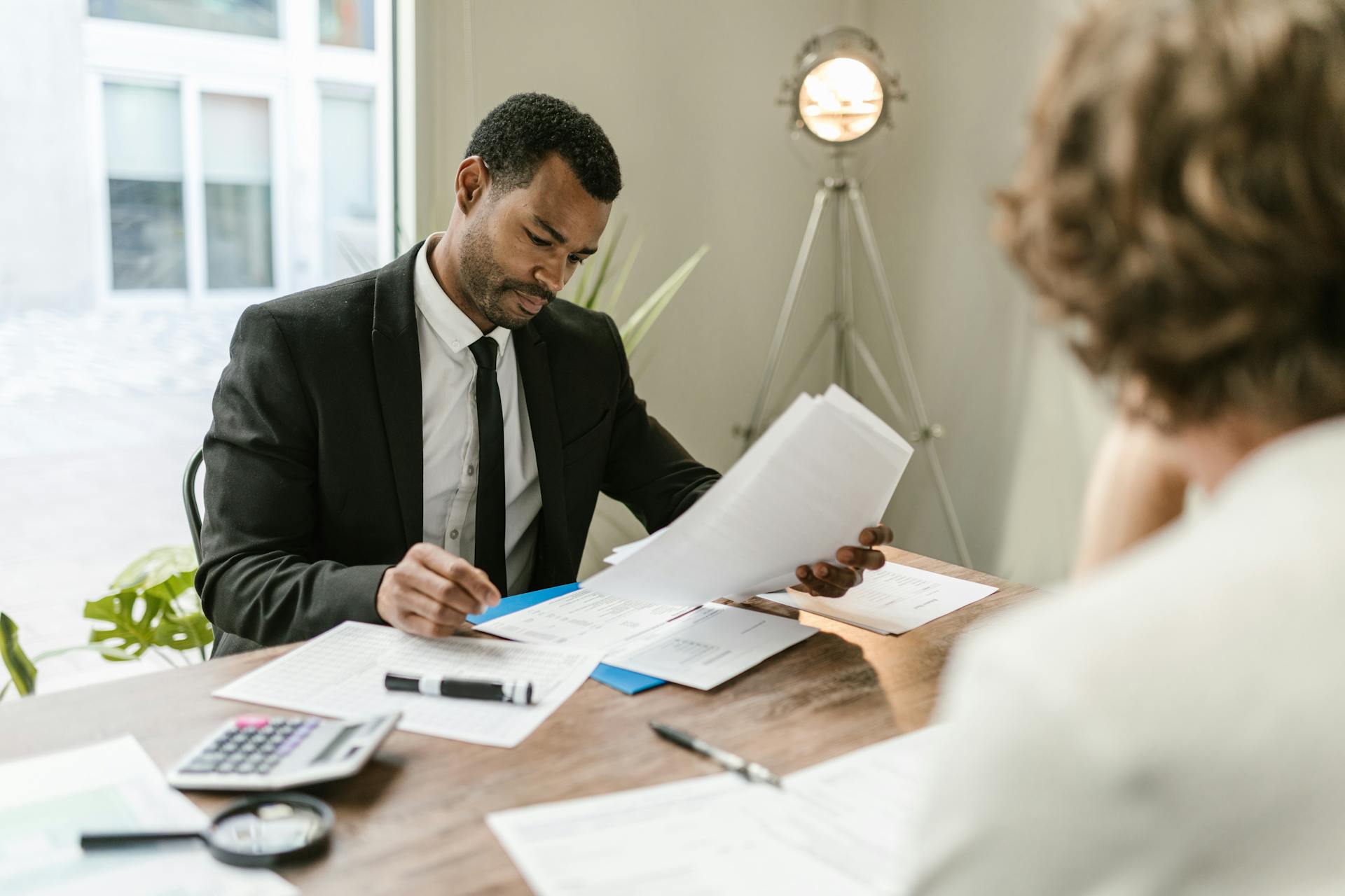 Professional businessman reviewing documents at a desk in a modern office setting.