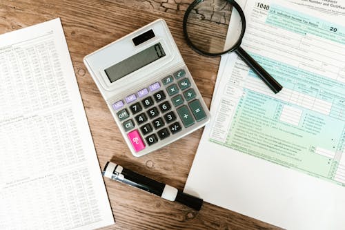 Free Gray Calculator and Black Magnifying Glass on Brown Wooden Surface Stock Photo