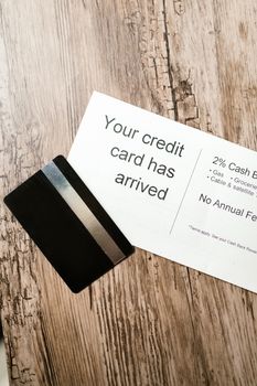 Close-up view of a credit card and welcome letter on a wooden table, emphasizing finance and banking.