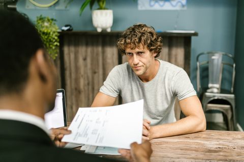 Dos hombres conversan sobre documentos en una reunión de negocios en una oficina moderna.