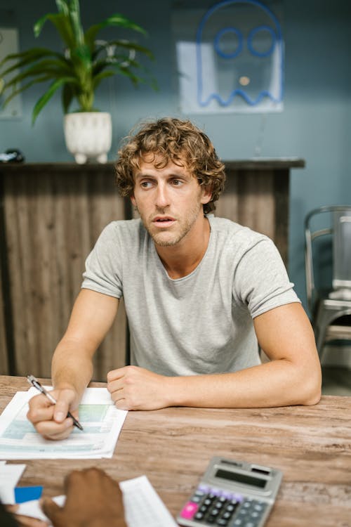 Man in Gray Crew Neck T-shirt Sitting by Wooden Table