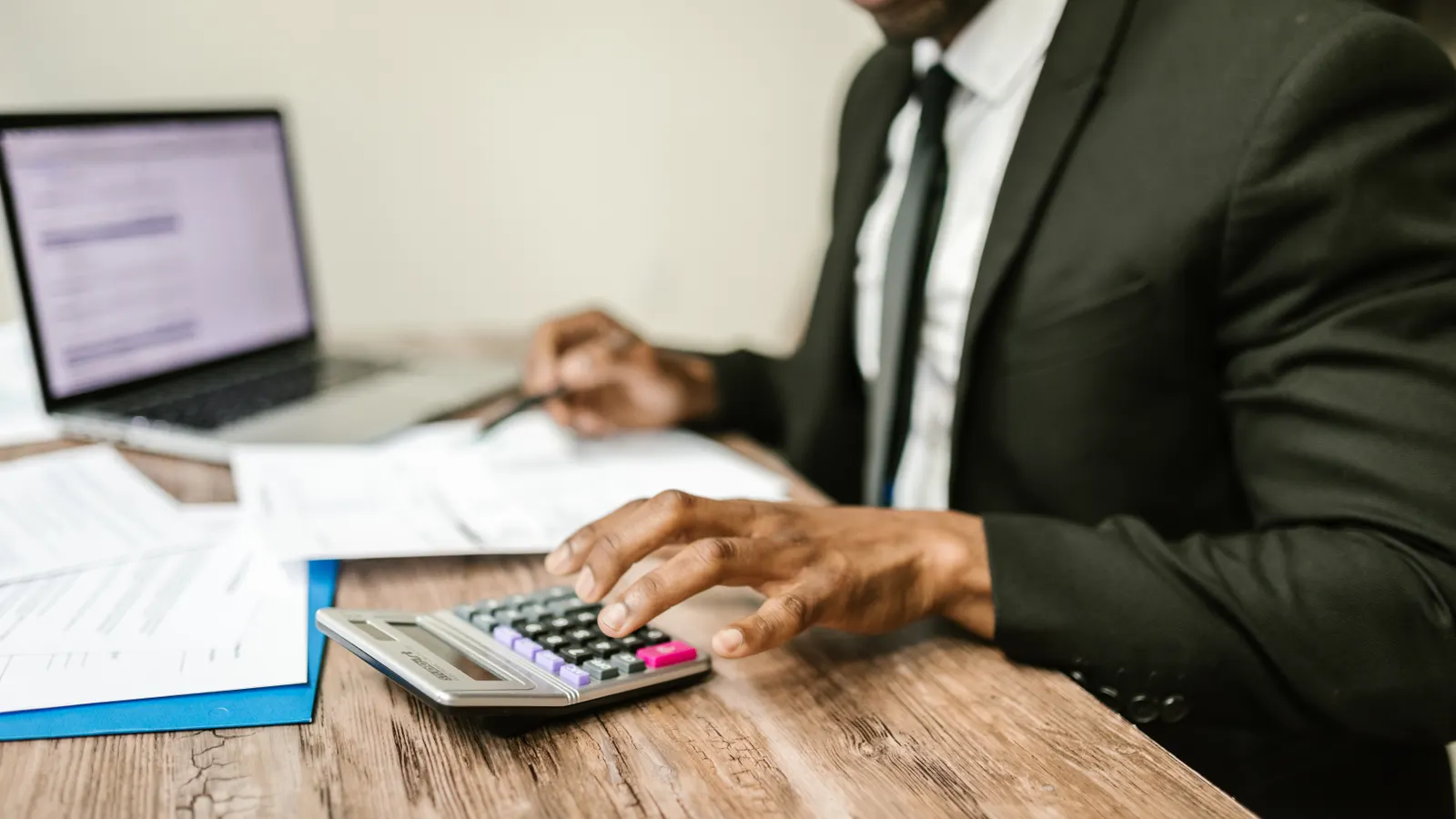 Founder at a desk with a laptop and calculator working through numbers