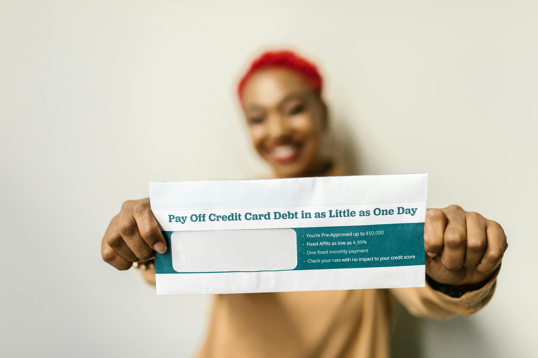 Woman presenting an envelope with a credit card debt offer, blurred background