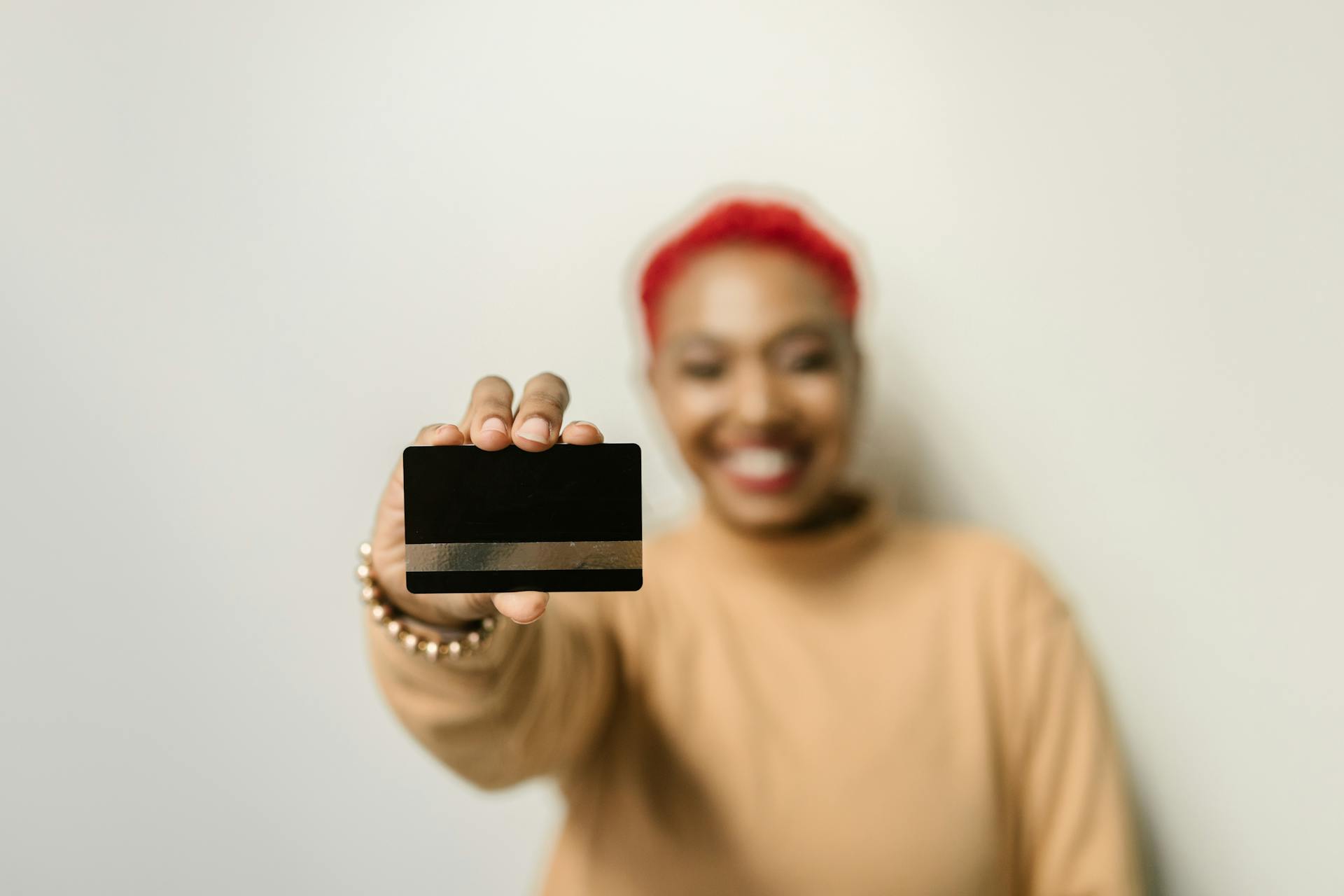 Close-up of a credit card held by a smiling person, emphasizing modern finance and personal identity.