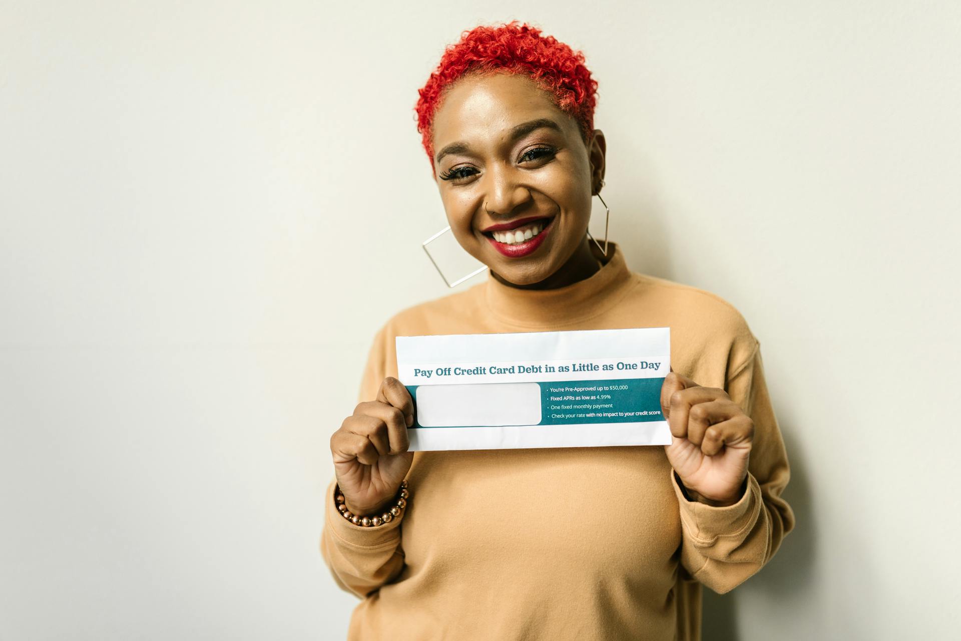 Happy woman with red hair holding an envelope for debt payoff.